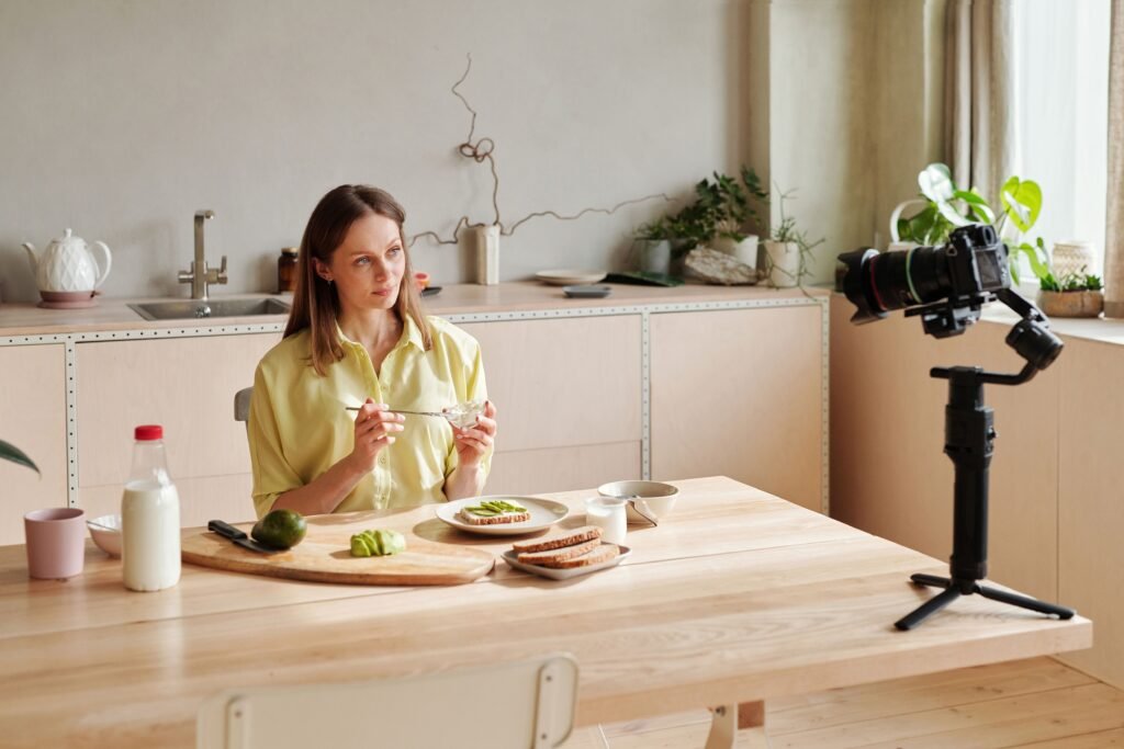 Woman recording a healthy breakfast vlog in a modern kitchen setting, featuring avocados.